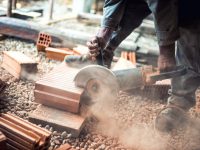 Industrial construction worker using a professional angle grinder for cutting bricks and building interior walls