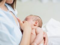 Mother breastfeeding a new born baby boy in a hospital room